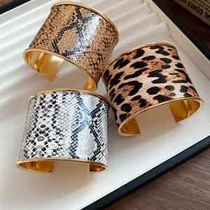 Macro view of leopard and snakeskin print wide cuff bracelets with gold metal lining