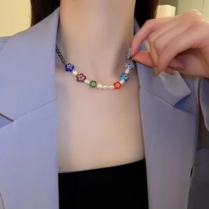 Detailaufnahme einer bunten Blumen-Perlenkette mit weißen Perlen an einer feinen Kette