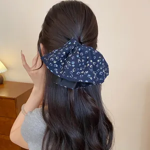 Dettaglio di uno scrunchie vintage in tessuto floreale blu navy su lunghi capelli castani