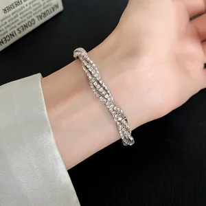 Detailed macro view of an elegant multi-layer rhinestone twisted geometric bracelet on a wrist.