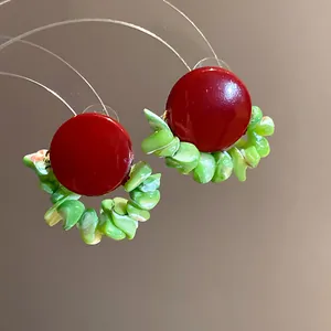 Detailed macro view of vintage red stud earrings featuring green shell chip tassel accents.