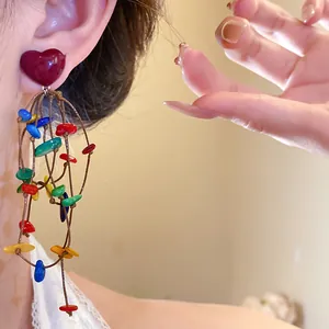 Macro close-up view of colorful bohemian heart shell tassel earrings worn on ear