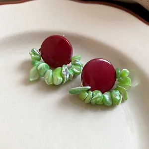Detail view of retro red stud earrings accented with green shell fragments