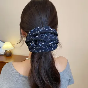 Vista dettagliata di un elastico per capelli vintage in tessuto floreale blu navy indossato