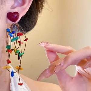 Macro shot of colorful shell tassel earrings featuring a chic dark red heart stud.