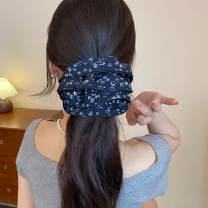 Vista dettagliata di uno scrunchie in tessuto a fiori vintage su capelli lunghi scuri