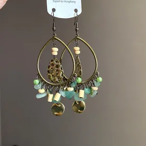 Detailed view of Bohemian teardrop earrings with green natural stones and wood beads.