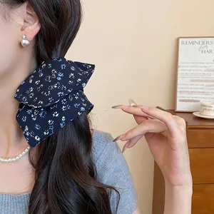 Dettaglio di un elastico per capelli in tessuto floreale blu scuro indossato da una modella
