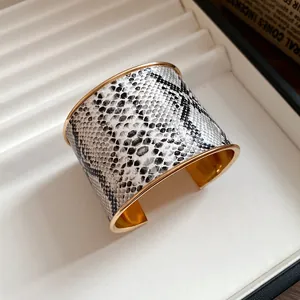 Close-up of a vintage wide gold cuff bracelet with monochrome snakeskin leather