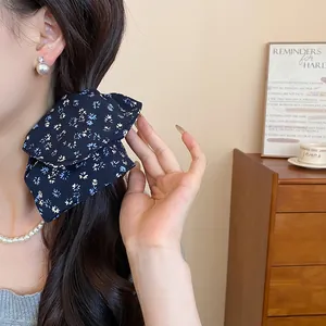 Dettaglio ravvicinato di un elastico vintage in tessuto floreale blu scuro tra i capelli