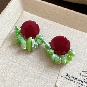 Close-up detail of vintage red stud earrings featuring unique green shell stone chips