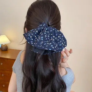 Dettaglio di un elastico per capelli floreale retrò blu navy su lunghi capelli castani.