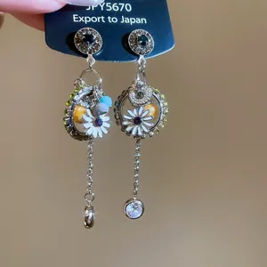 Close-up of bohemian earrings featuring daisy flowers and long crystal tassels
