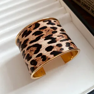 Detailed shot of a wide leopard print cuff bracelet with polished gold metal edges.