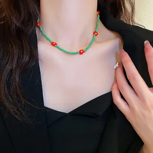 Detaillierte Nahaufnahme einer süßen grünen Perlenkette mit roten Blumen am Mode-Model