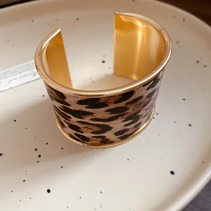Detail of leopard print leather texture and gold-tone metal interior on wide cuff bracelet