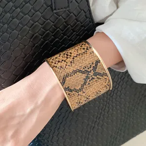 Close-up of a vintage wide python print leather cuff bracelet with gold edges.