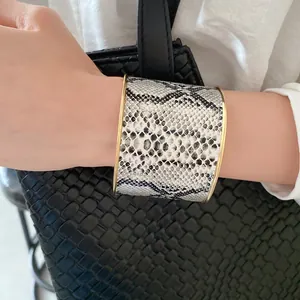 Close-up of elegant wide snakeskin pattern cuff bracelet with golden metallic edges