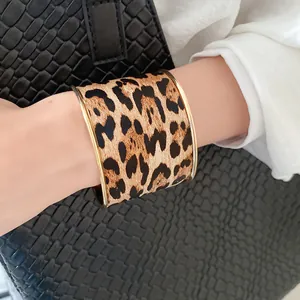 Macro view of a stylish leopard print wide open cuff bracelet on a model wrist