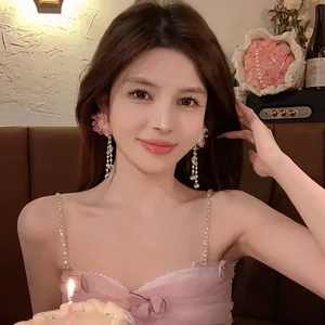 Elegant Asian model wearing pink fabric flower drop earrings with long pearl tassels at a party
