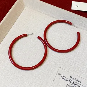 Macro view of bright red glossy hoop earrings on textured display board