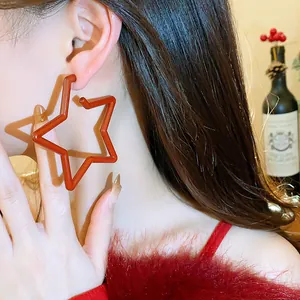 Elegant red star earrings worn by model, perfect for festive and stylish occasions.