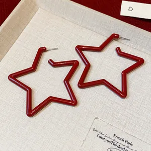 Detailed macro shot of elegant red star-shaped hoop earrings on beige fabric base