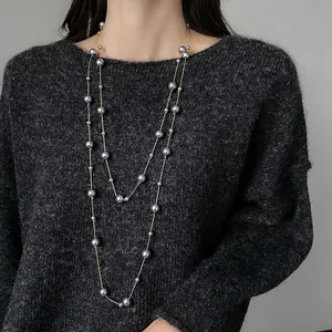 Elegante collana lunga a doppio strato con perle grigie su modella sopra maglione grigio