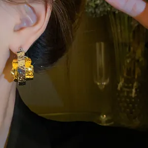 Close-up view of elegant gold and silver textured double-layered hoop earrings on model ear.