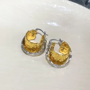 Detail view of gold and silver double-layered hoop earrings with crumpled metal texture
