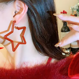 Close-up of large red star hoop earrings on model for festive look