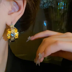 Detailed view of stylish two-tone crumpled metal hoop earrings worn on an ear