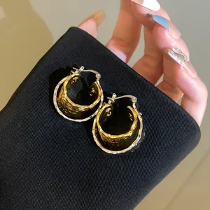 Mixed metal wrinkled double-layered hoop earrings displayed on black fabric