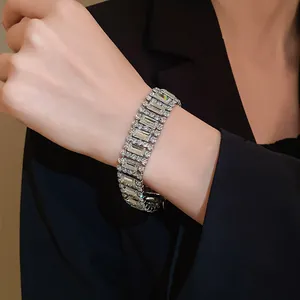 Close-up view of a luxury geometric crystal bracelet worn on a wrist with black blazer.