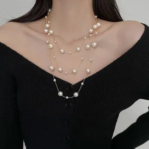 Primo piano di una lunga collana di perle multistrato in stile francese su un modello in maglia nera