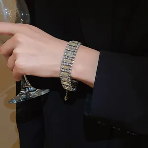 Elegant close-up of geometric crystal bracelet worn by a model holding a glass of wine