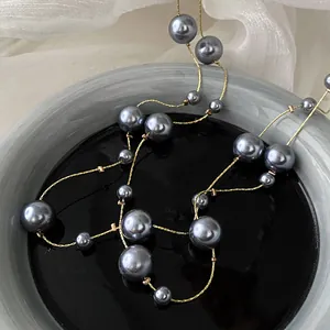 Dettaglio della collana lunga vintage in stile francese con perle grigie e catena d'oro