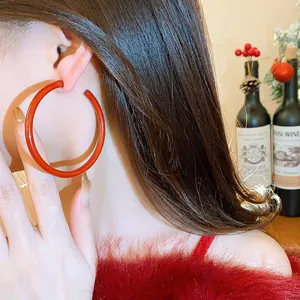 Close-up view of stylish large red C-shaped hoop earring for festive New Year look