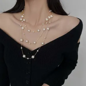Dettaglio di una collana lunga a tre strati di perle su un cardigan in maglia nero