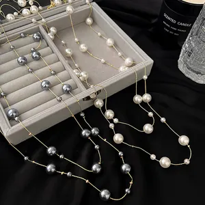 Dettaglio della collana lunga con perle in stile francese nei colori grigio e bianco