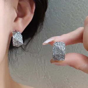 Vista detallada de pendientes geométricos en forma de C con textura de plata rugosa