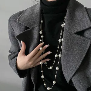 Dettaglio di una lunga collana di perle vintage francese abbinata a un cappotto grigio