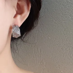 Primer plano de elegantes pendientes geométricos plateados con textura arrugada