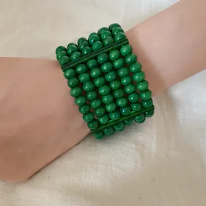Detail view of ethnic bohemian multi-layer bracelet featuring vibrant green wooden beads