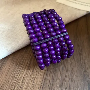 Close-up of purple multi-layer wooden bead bracelet with textured metal bar detail