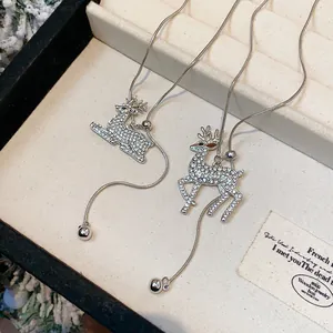 Dettaglio di collane con ciondolo a renna in strass su vassoio per gioielli crema.