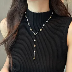 Dettaglio dell'elegante collana a Y con perle e grani dorati testurizzati