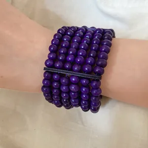 Close-up detail of a multi-layer purple wooden bead bracelet featuring ethnic retro design