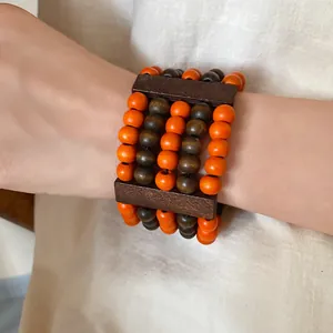 Detail of ethnic style multi-layer bracelet with orange and brown wooden beads