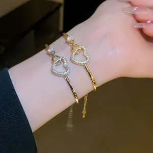 Detailed view of elegant gold and silver heart zircon bangles on a lady's wrist